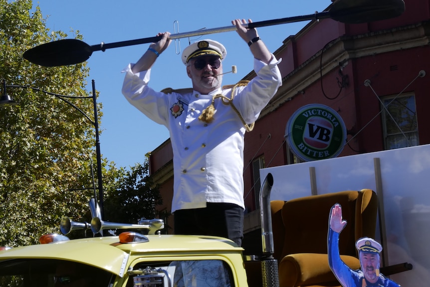  A man in a mocked-up navy uniform made from a chef's white jacket and golden curtain rope for a navy aiguillette