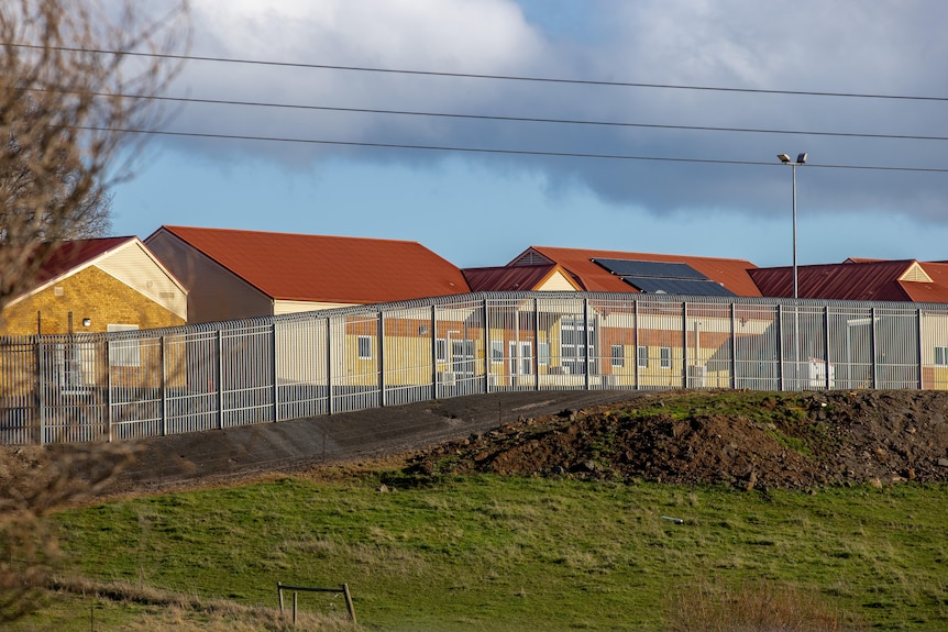 The buildings of the Ashley Youth Detention Centre sit behind a tall fence.