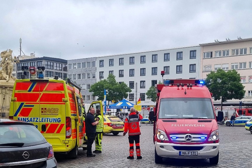 Yellow and red emergency vehicles are parked in a city square in Germany.