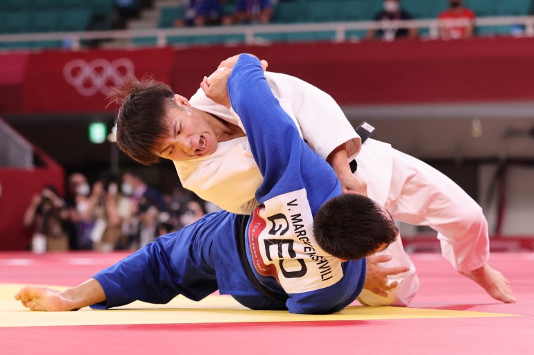 Judo wrestlers on mat.