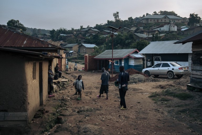 Children watch wounded pro-government militiamen walk in the courtyard of a hospital in Kanyabayonga,