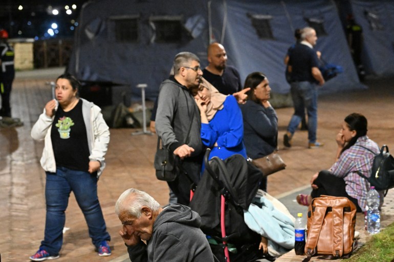 Inhabitants gather near a makeshift camp set up by the civil protection in the port area after a flurry of tremors of a strength not seen in decades was registered in Pozzuoli, on May 21, 2024 - Emergency services in the area reported cracks and pieces falling from buildings, while amateur video from a supermarket in the town of Pozzuoli showed bottles strewn across the floor after being shaken off shelves.