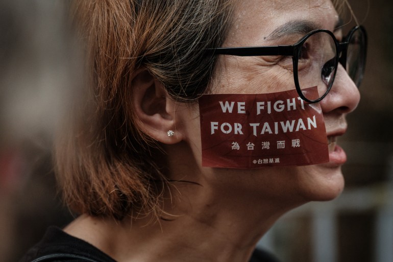 A protester photographed in profile. She has 'We fight for Taiwan' painted on her cheek.