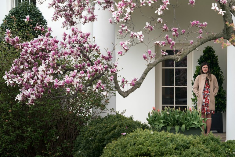 Madeleine Westerhout stands outside the White House, under the branch of a blooming cherry blossom tree.