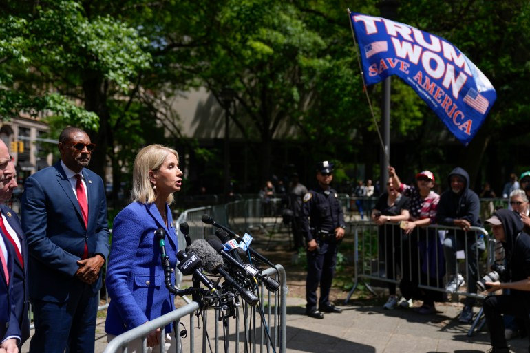 Illinois Representative Mary Miller speaks to the press in an outdoor news conference in New York, as a Trump supporter waves a flag reading, "Trump won."