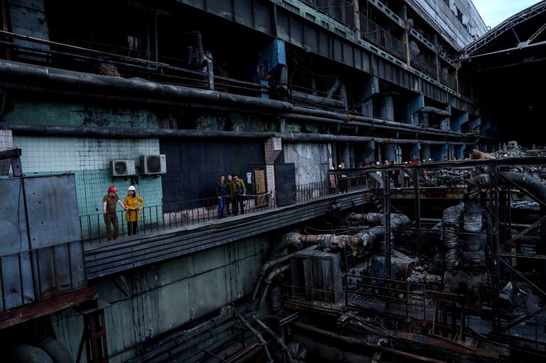 German's Foreign Minister Annalena Baerbock speaking to Ukrainian Energy Minister Herman Halushchenk. They are on a walkway inside a power station destroyed in a Russian attack.