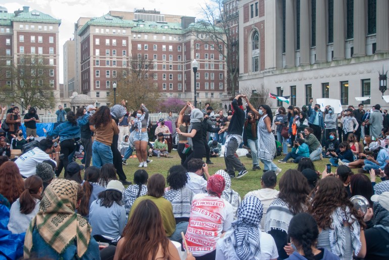 Student protesters dance together on the Columbia University lawn, surrounded by onlookers.