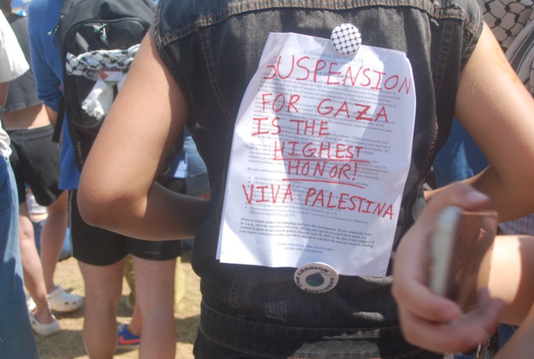 A student has a Columbia University letter pinned to the back of her jacket, with red ink scrawled over it reading: "Suspension for Gaza is the highest honor. Viva Palestina."