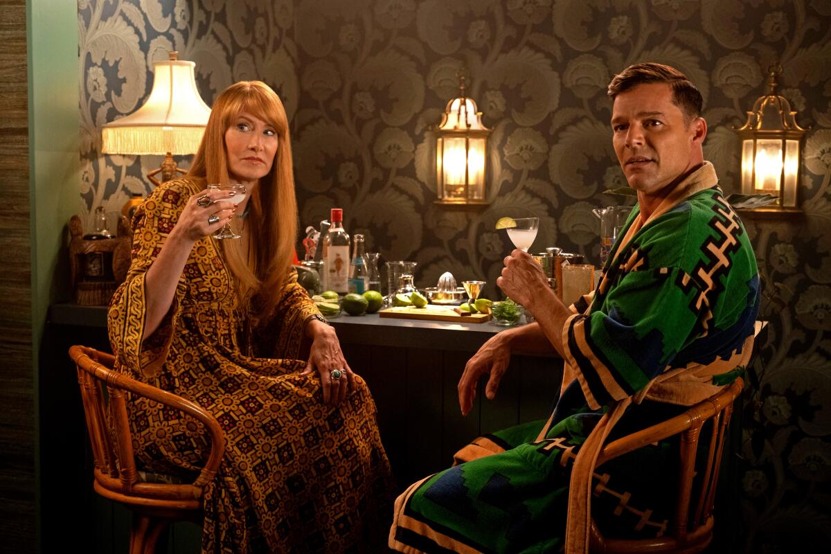 A man and woman sit at a bar with drinks in hand.