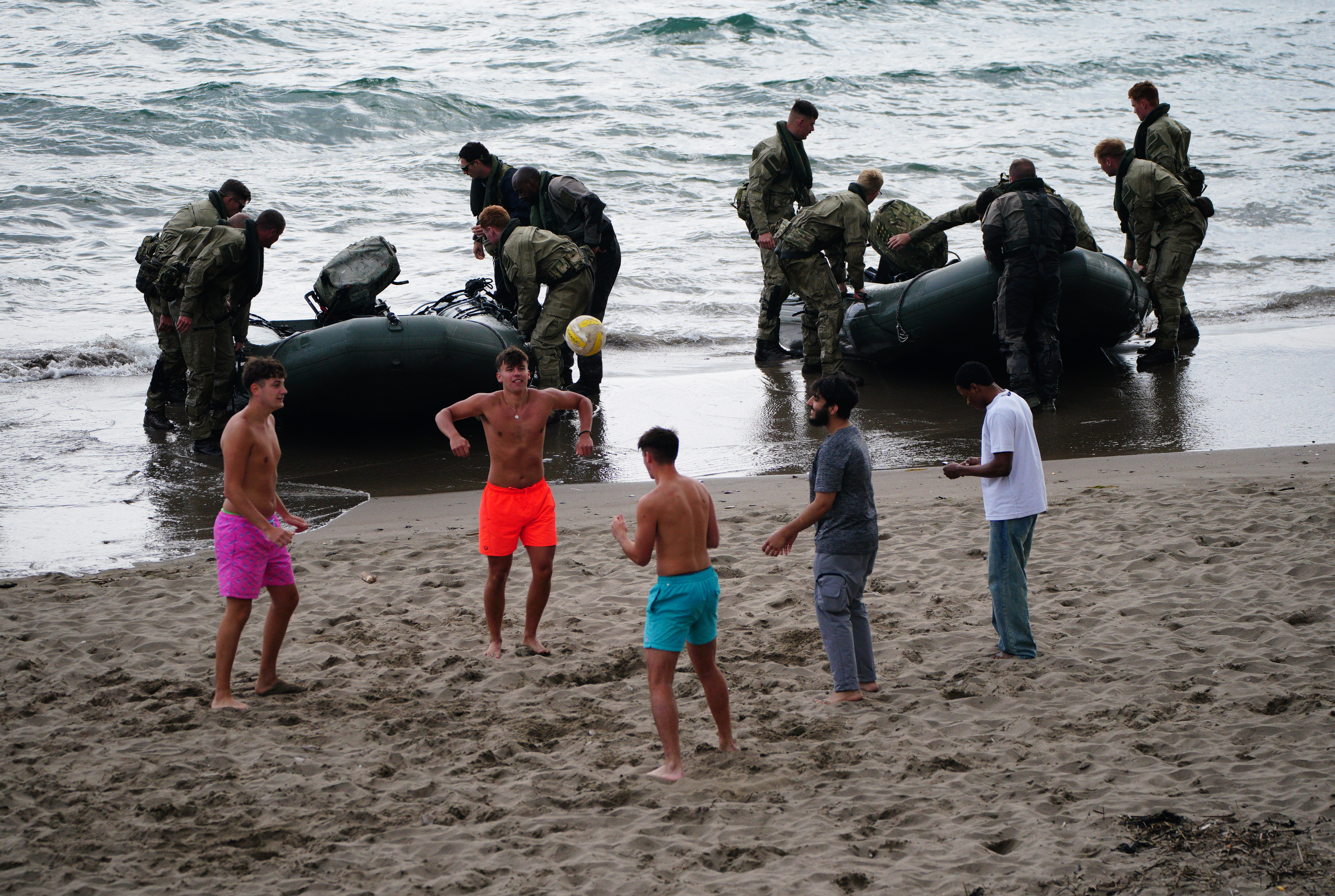 Royal Marines commandos ­re-enact a daring World War Two raid in Cornwall — as beach-lovers lark about with a football