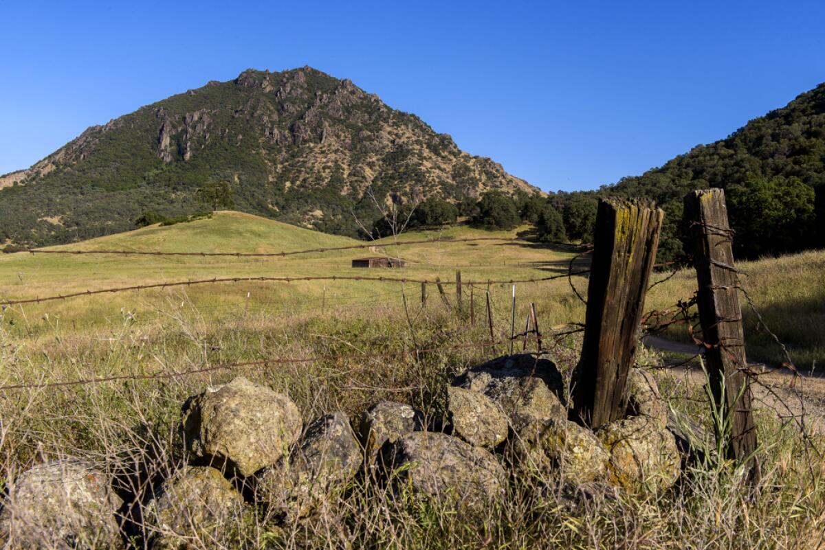 A lava dome rises above rolling green pasture.