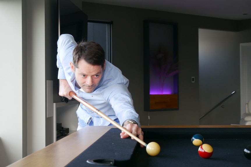 A man lines up a pool cue. 