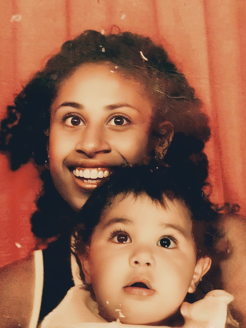 A vintage photo of a little baby sitting on a smiling woman's lap