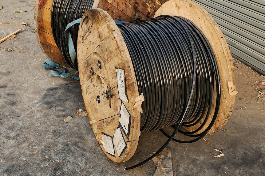 Two large rolls of copper cabling in an outdoor carpark.