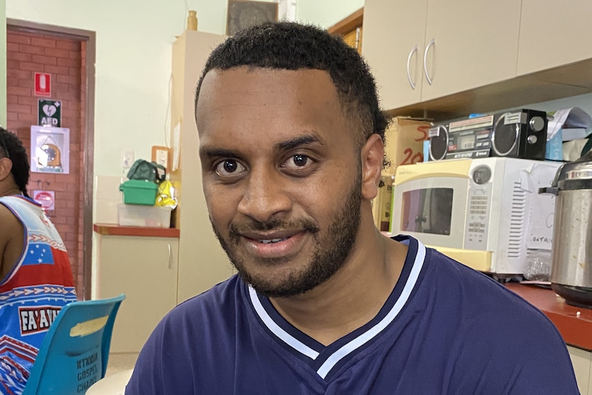 A man in a blue t-shirt with writing saying 'Chicago' sitting down. 