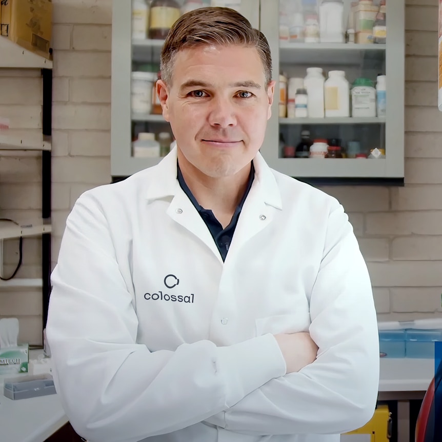 A man wearing a lab coat with his arms crossed.