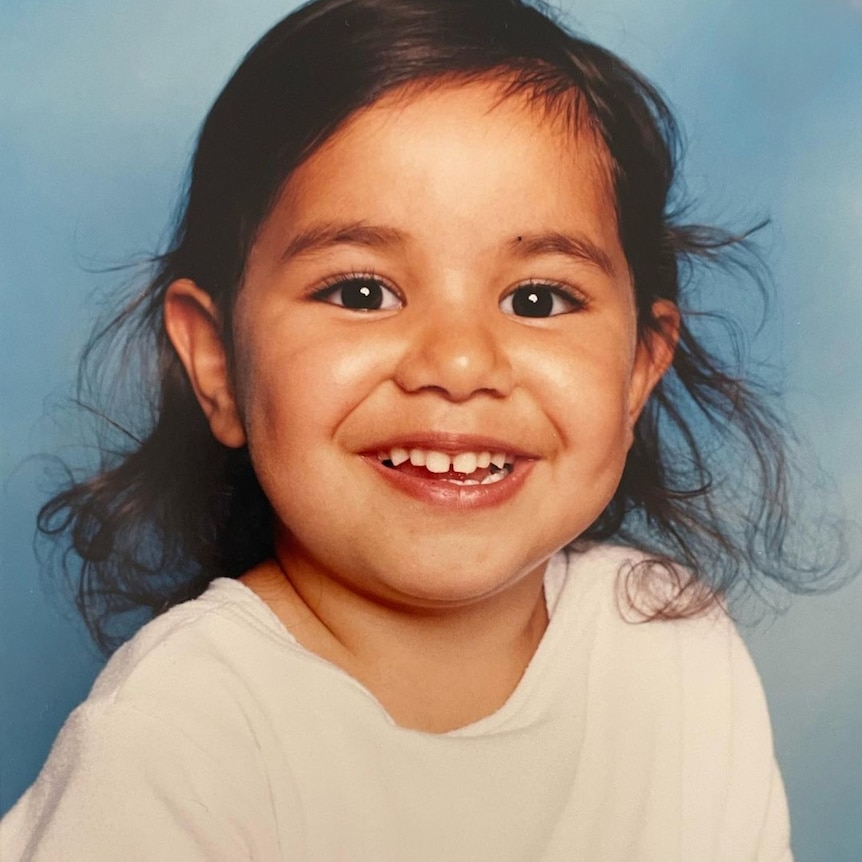 A head and shoulders image of a cute little blak girl, grinning.