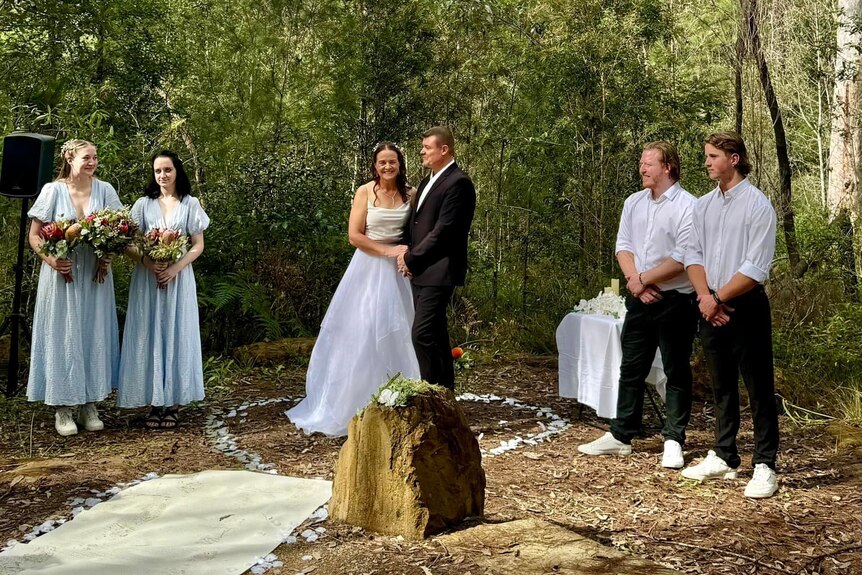 Newlyweds and bridal party in a bush setting.