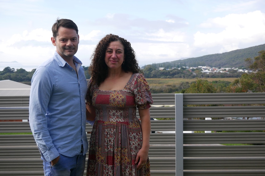 A man and a woman stand on the deck of their house in Albany.