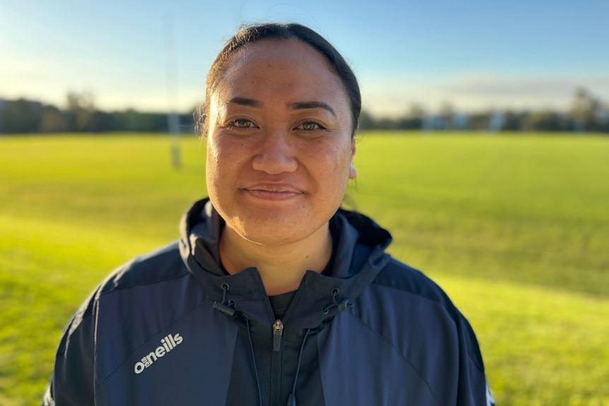 a woman wearing a blue coat on a rugby field