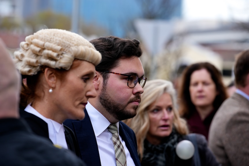 A lawyer accompanies Bruce Lehrmann into the court room followed by media. 