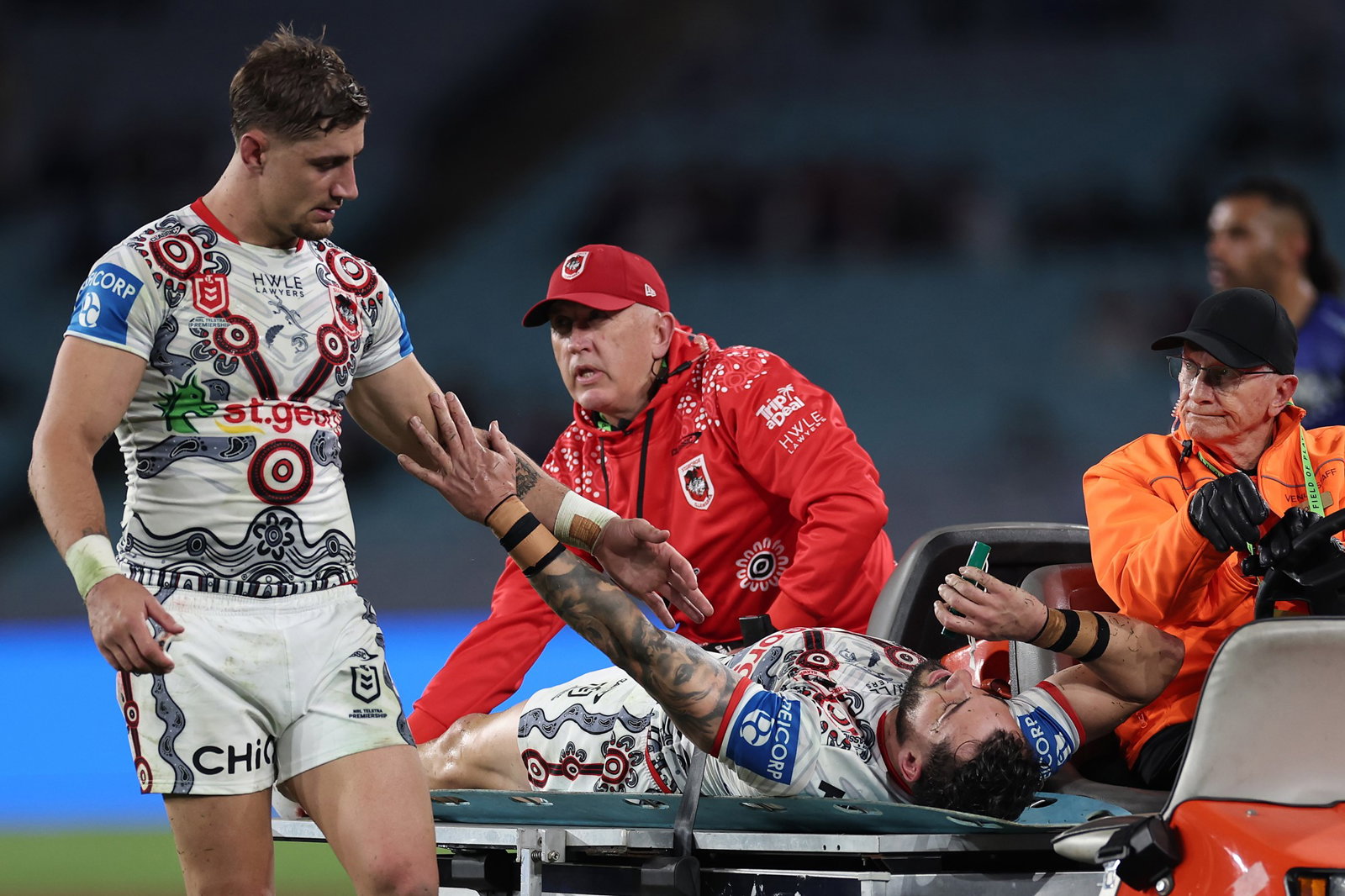 Zac Lomax reaches out to touch Dragons teammate Jack Bird as he leaves an NRL game on a medicab.