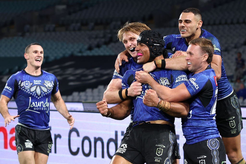 Bulldogs players jump on Stephen Crichton after a try in an NRL game against the Dragons.