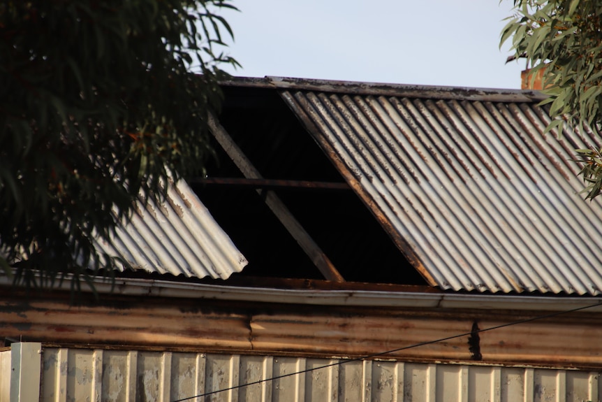 A tin roof partially blackened and damaged by fire