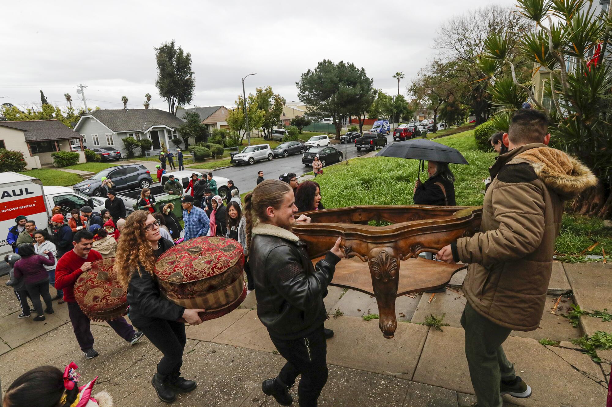 Volunteers help a woman move into a vacant house.