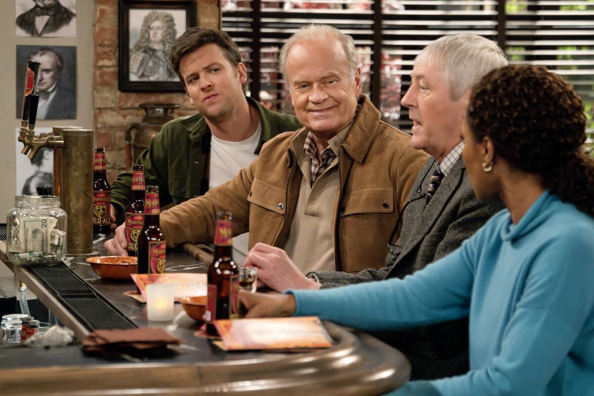 Three men and a woman sit at a bar with beers in a scene from the new "Frasier."