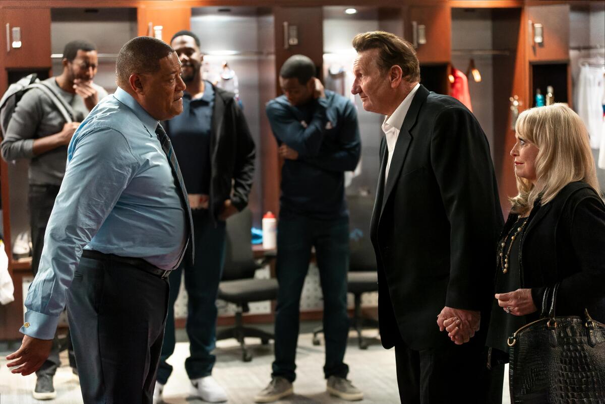 Three older people conversing in a locker room as younger people look on.