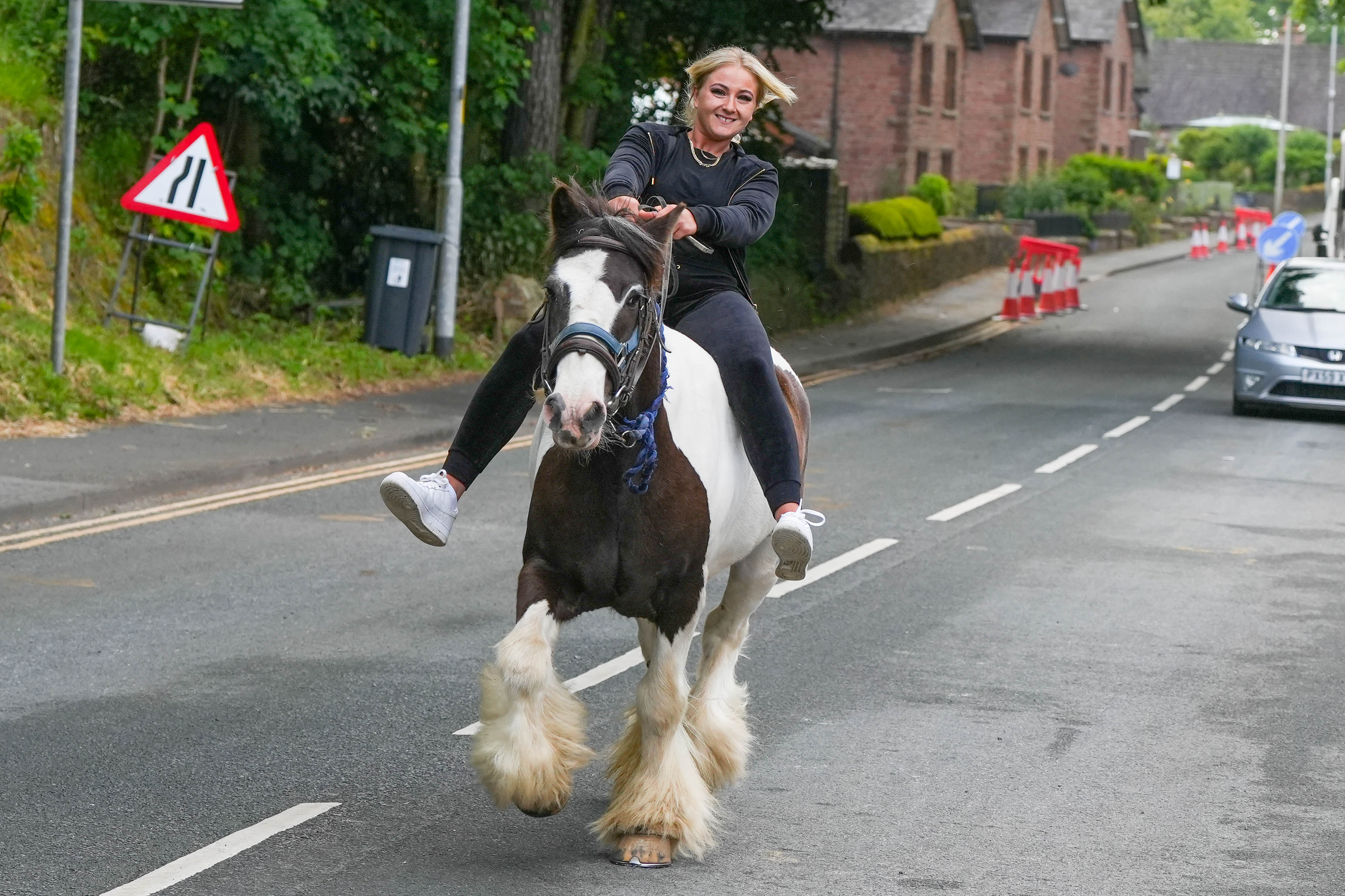 A woman rides a horse through the streets during the first day of the fair