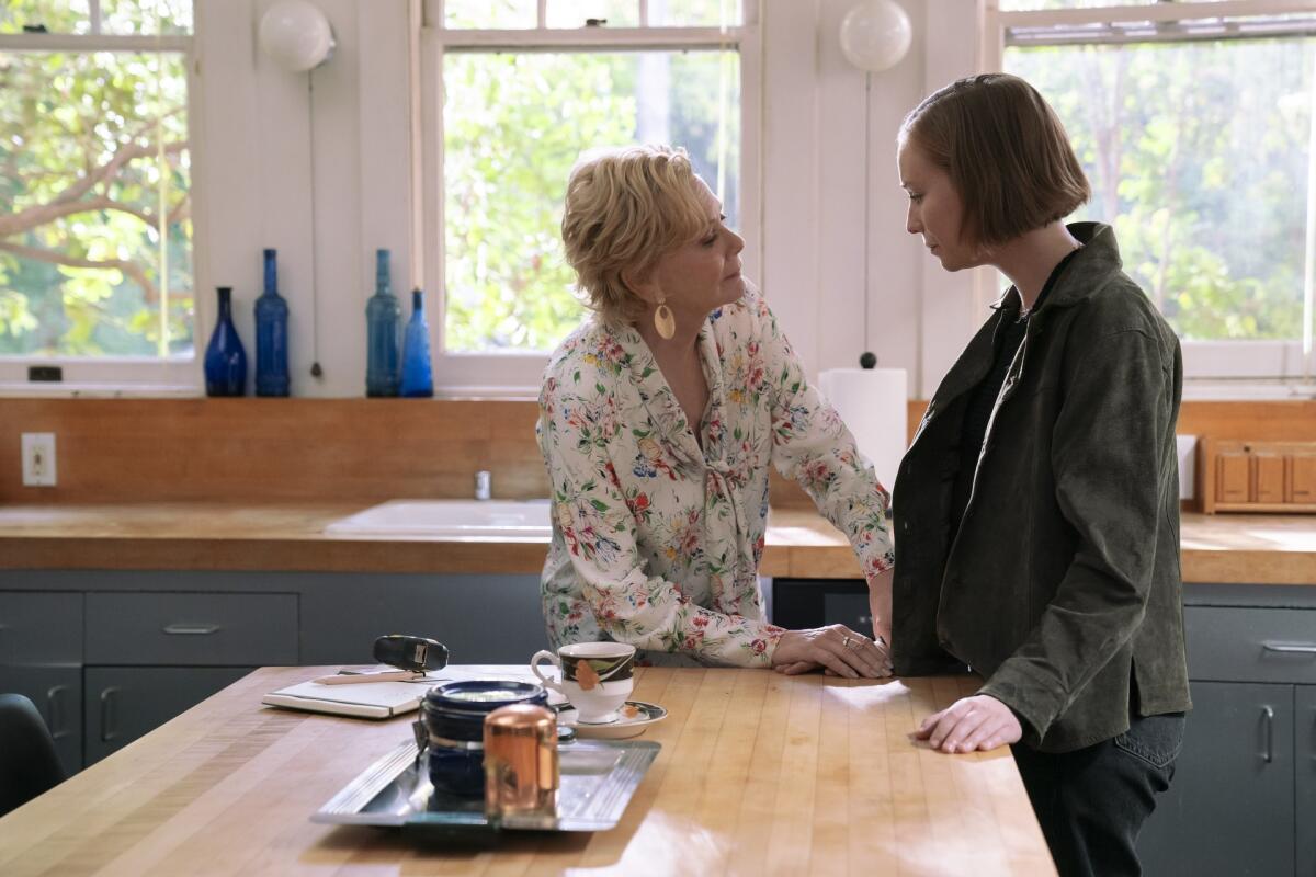 Two women talking in a kitchen.