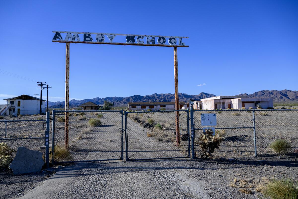  The faded Amboy School sign stands over a chain link fence