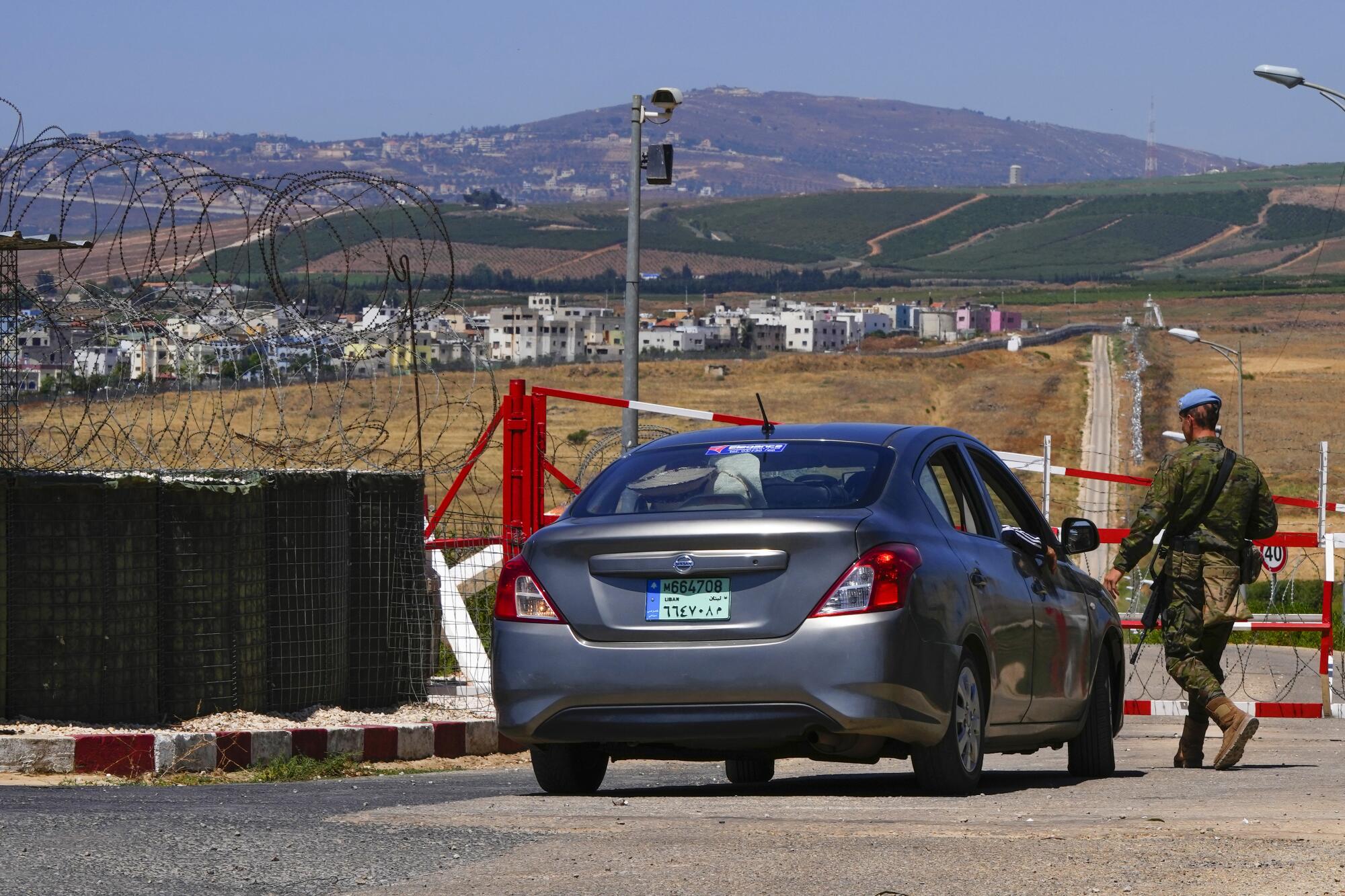 A U.N. Peacekeeper stops a car at a checkpoint on a road that leads t