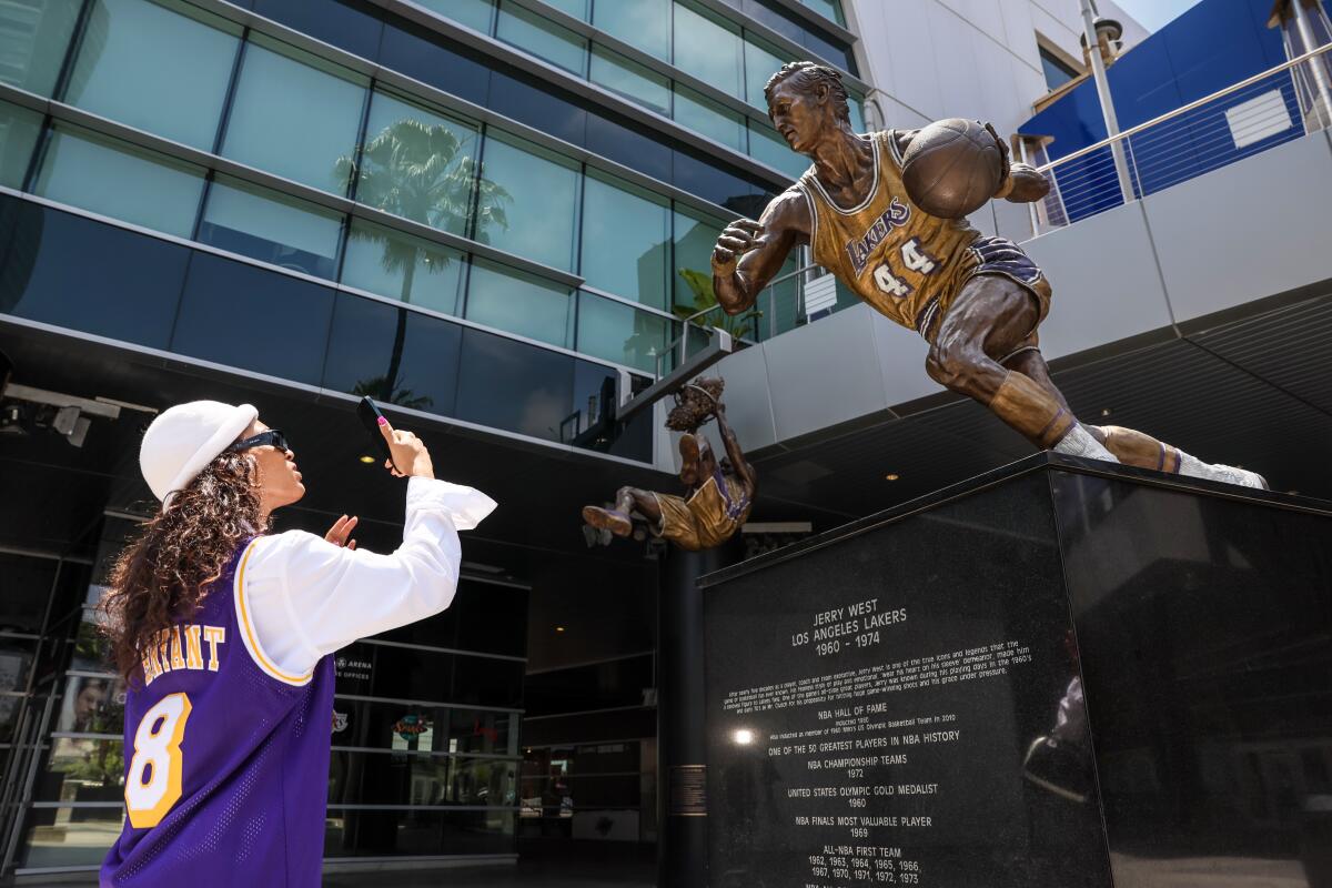 Sankara XT pauses to photograph a statue of Jerry West at Crypto.Com Arena after hearing the news of his death Wednesday.