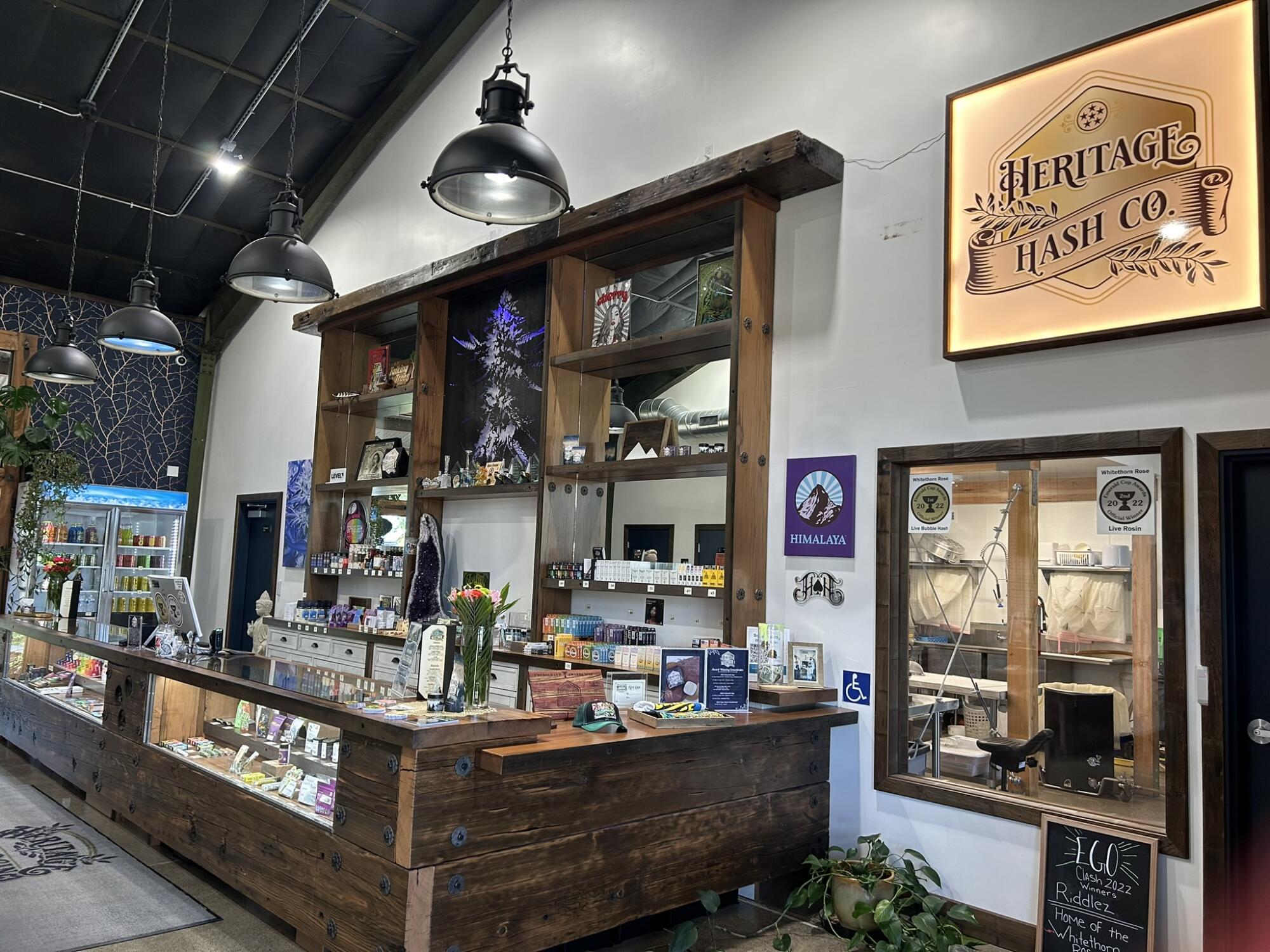 A cannabis dispensary counter with a window next to it that looks into an industrial-kitchen type room.