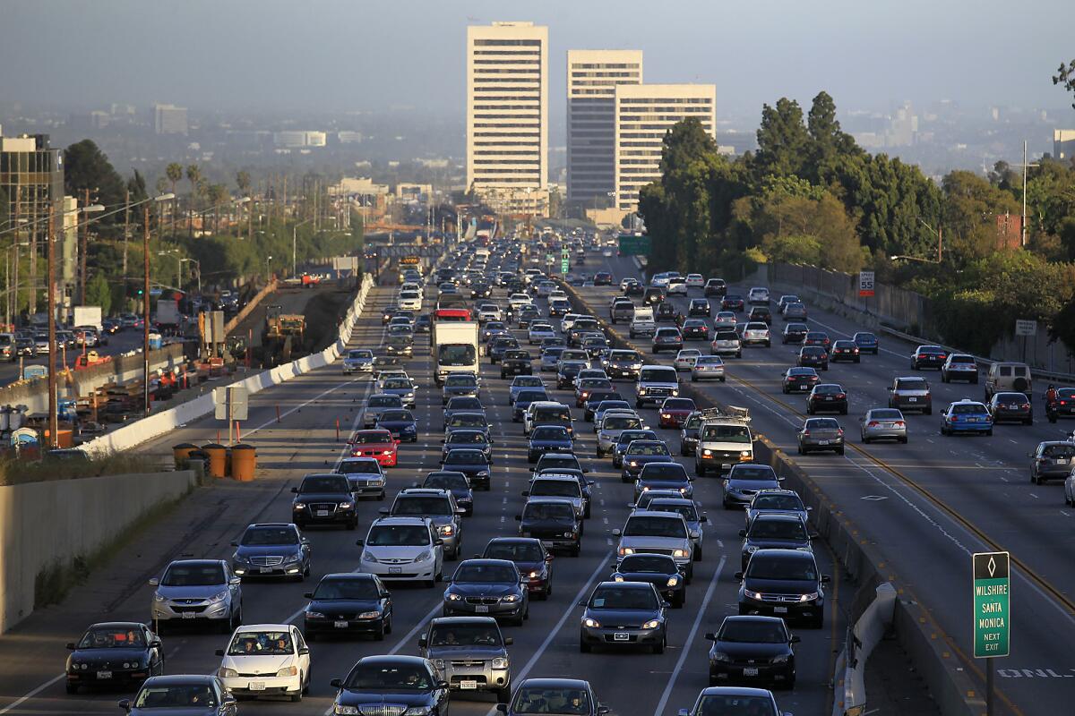 Traffic fills a freeway as office buildings rise in the background.