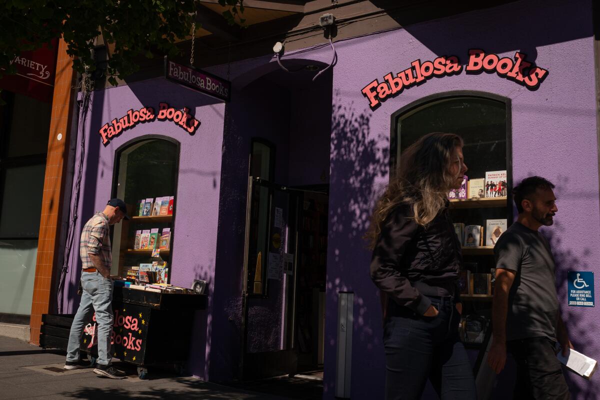A person looks at books in a window of a storefront with the words "Fabulosa Books" on it.