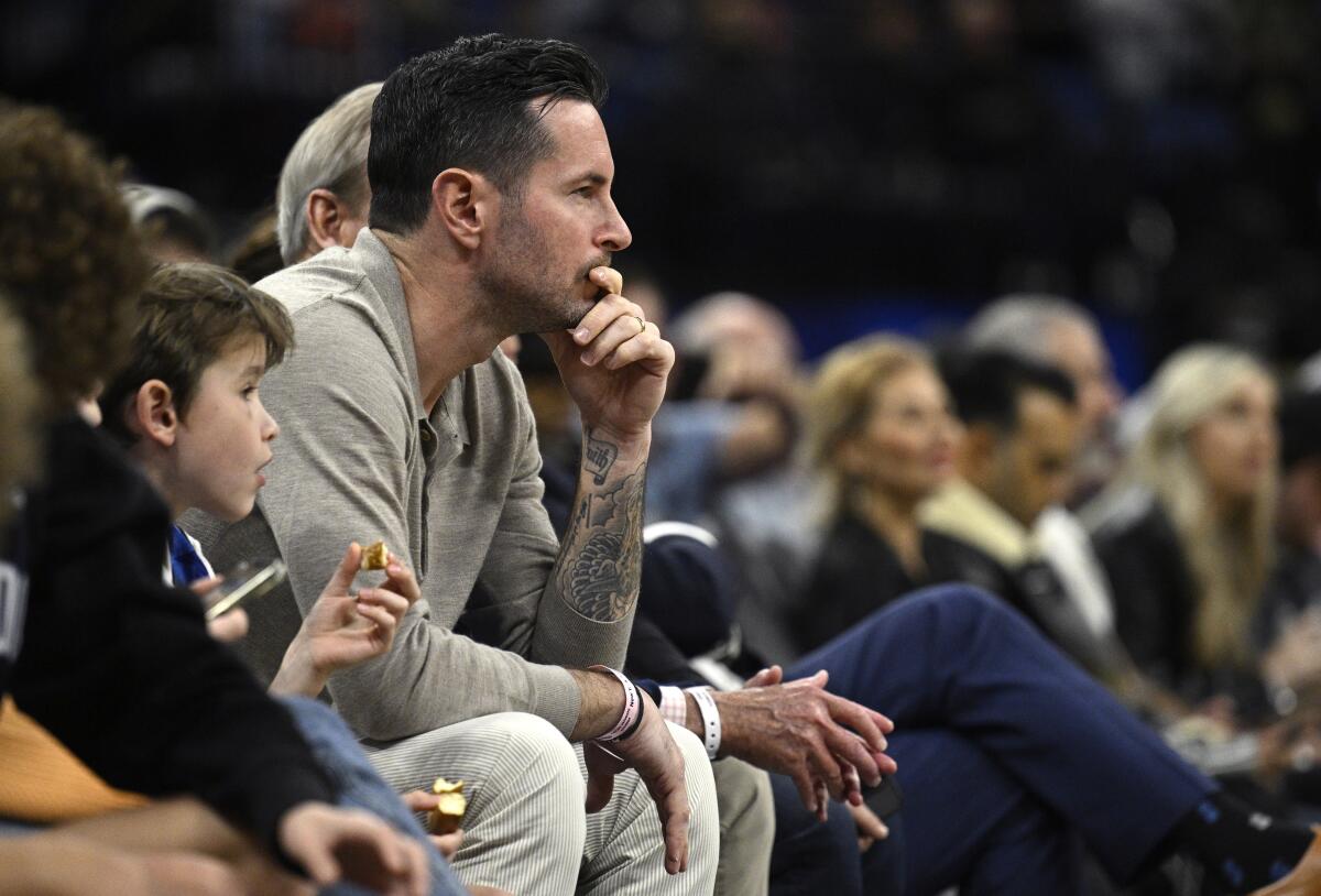 Former Orlando Magic guard JJ Redick, center, watches from a court side seat during the first half.