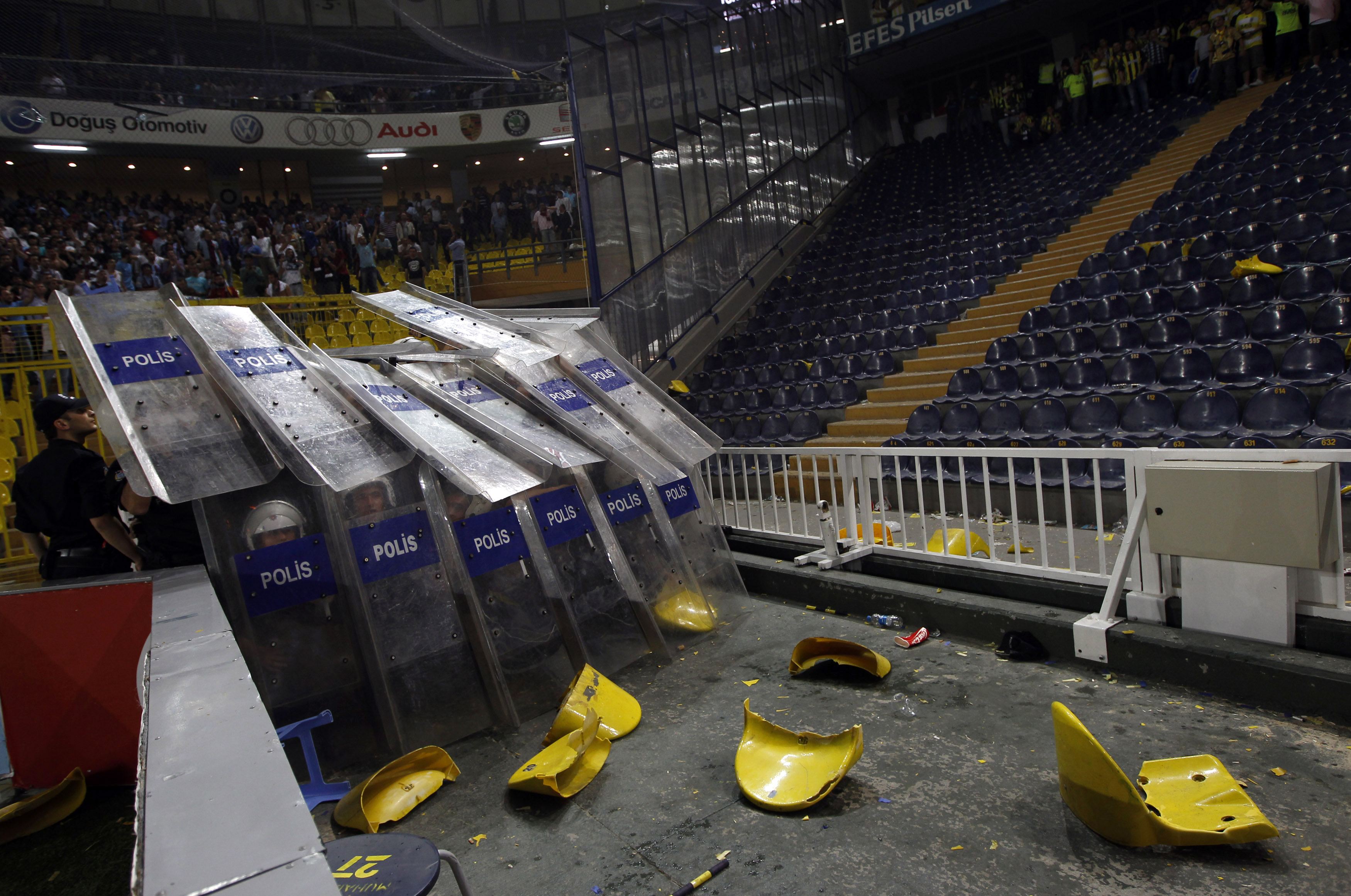 Turkish riot police shielding themselves from an angry mob of fans launching broken chairs at them