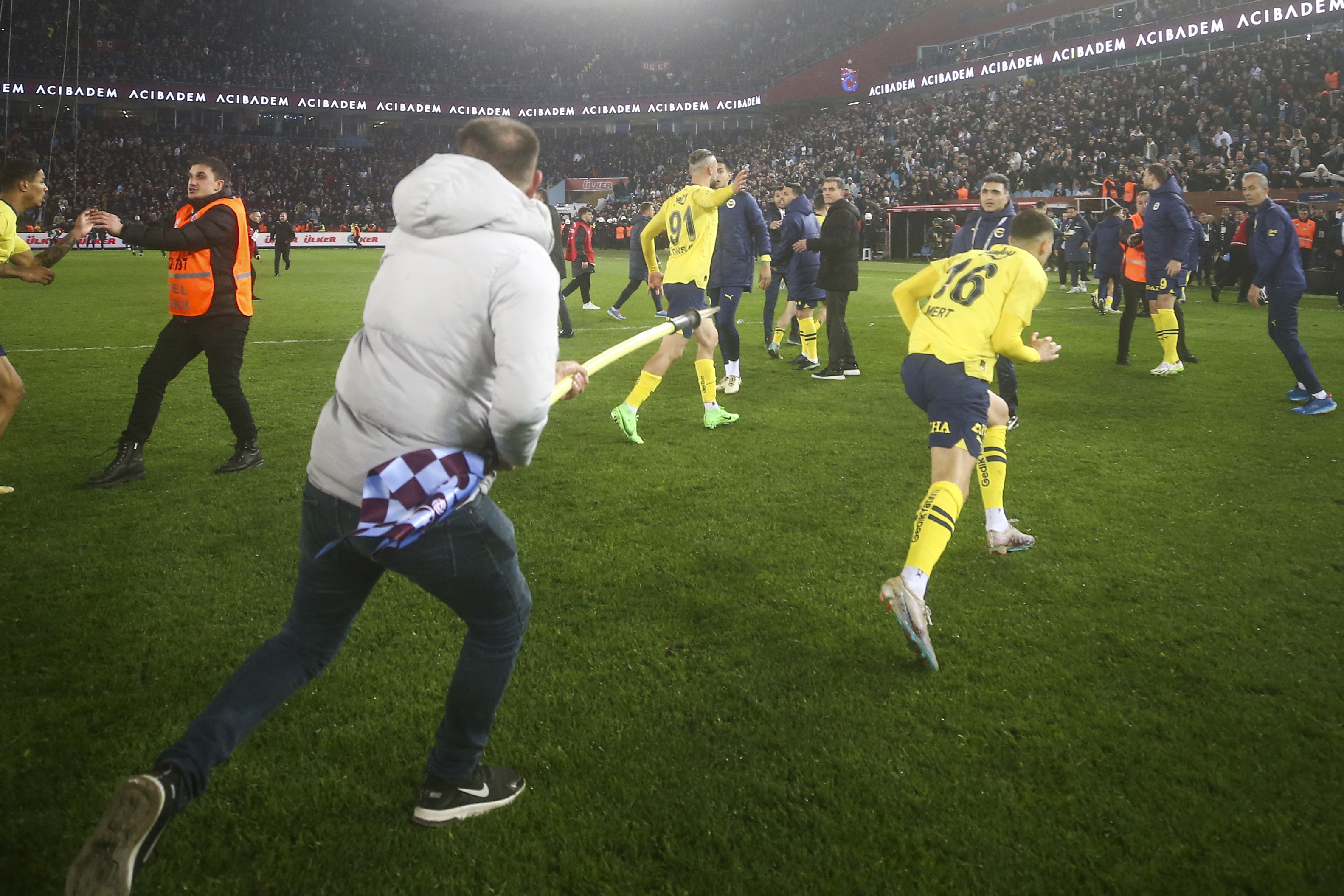 A crazed Trabzonspor supporter chased Fener players with the corner flag in a huge pitch invasion