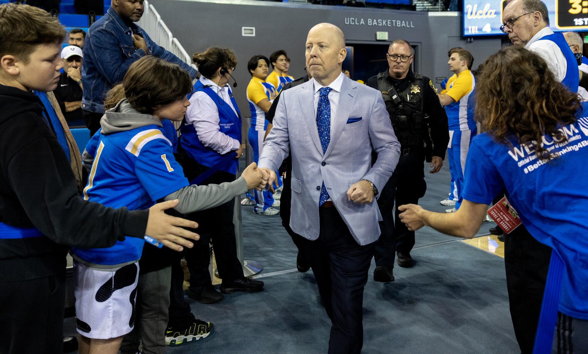 UCLA coach Mick Cronin fist-bumps fans before a game.
