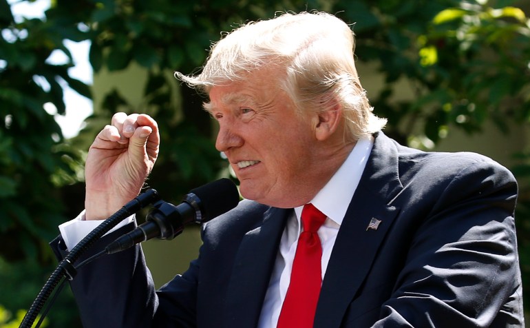 In 2017, Trump gestures while speaking into a microphone at an outdoor podium