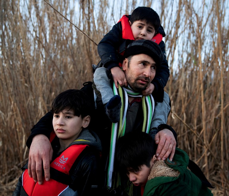 A man holds his three sons as migrants from Afghanistan arrive on a dinghy on a beach near the village of Skala Sikamias, after crossing part of the Aegean Sea from Turkey to the island of Lesbos, Greece, March 2, 2020. REUTERS/Alkis Konstantinidis/File Photo TPX IMAGES OF THE DAY SEARCH "GLOBAL POY" FOR THIS STORY. SEARCH "REUTERS POY" FOR ALL BEST OF 2020 PACKAGES.