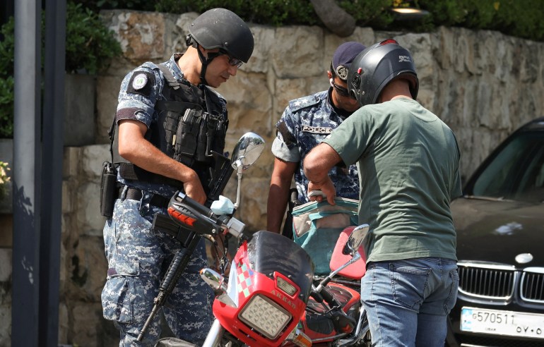 Lebanese police officers check a man on a motorbike near the US embassy in