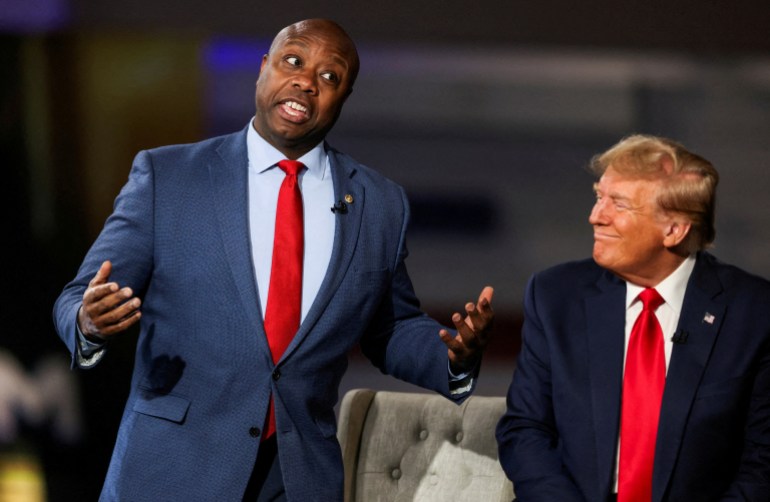 Tim Scott gestures next to Donald Trump