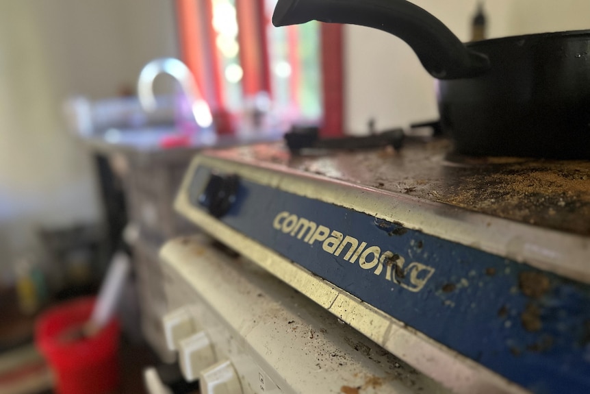 A dirty stove in a kitchen in a messy house.