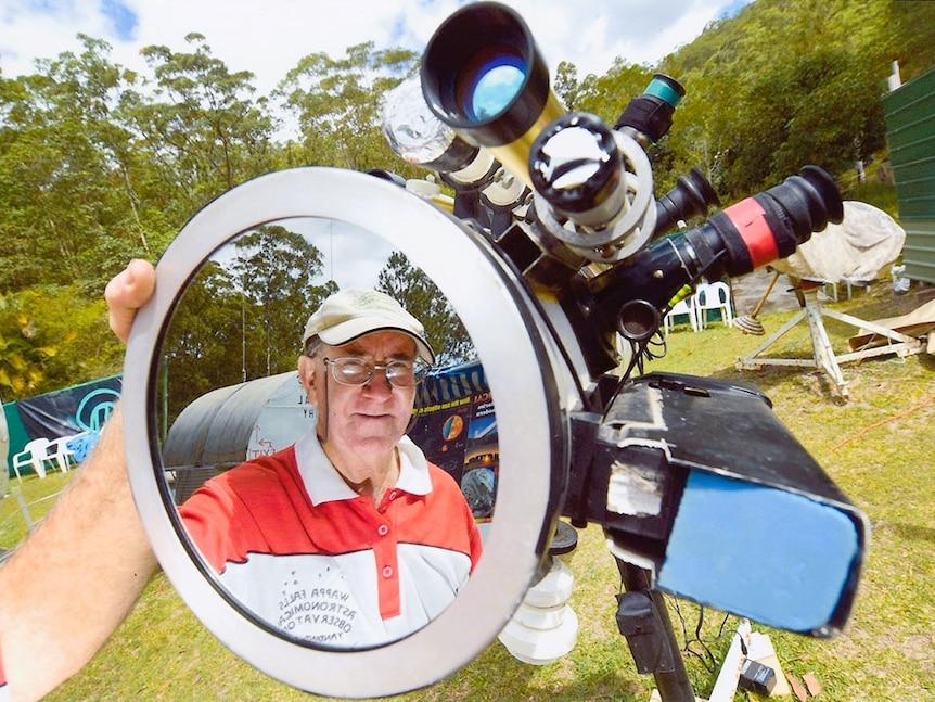 Owen Benedict's face is mirrored in a telescope.