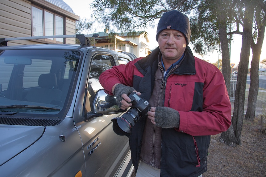 A photographer wears two heavy coats